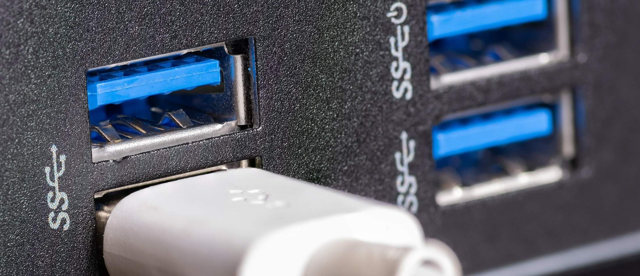 The image features a close-up view of four blue USB 3.0 ports on a sleek black device, highlighting the advanced connectivity options available. One of the ports is actively in use, with a white USB cable plugged in, which is especially essential for tasks such as retrieving deleted images from connected devices. The design elements underscore functionality while maintaining an elegant, modern aesthetic.